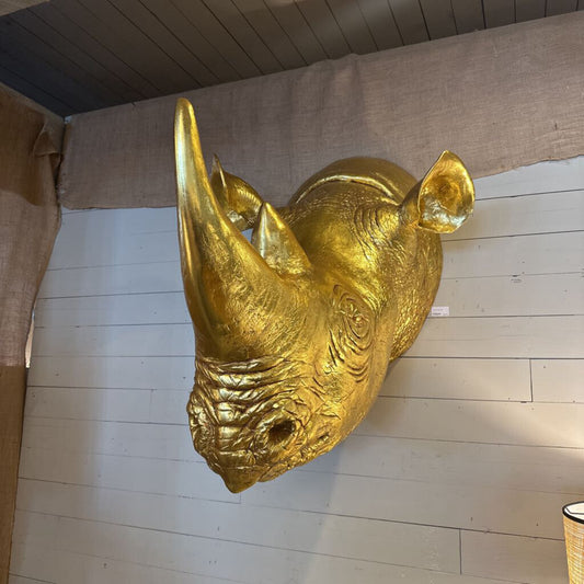 Gold rhinoceros head sculpture on a wooden floor
