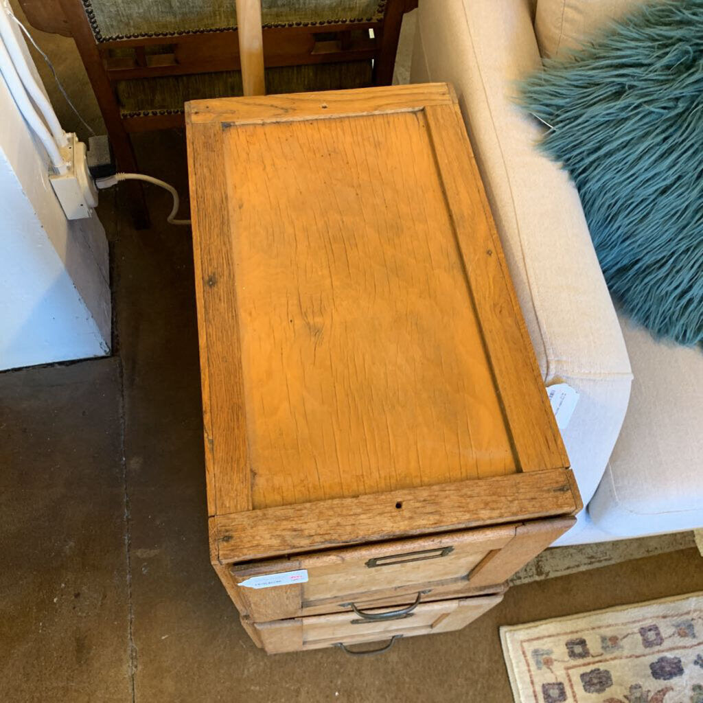 Wooden cabinet with drawers on a carpeted floor next to a sofa.