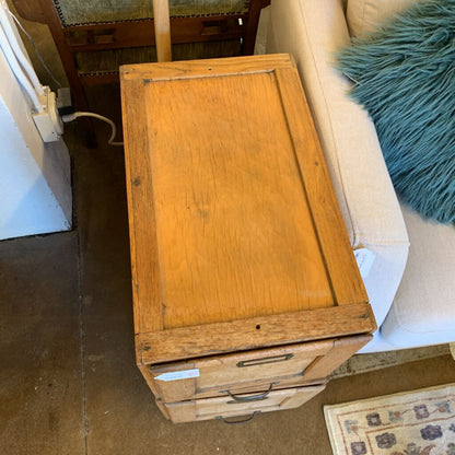 Wooden cabinet with drawers on a carpeted floor next to a sofa.