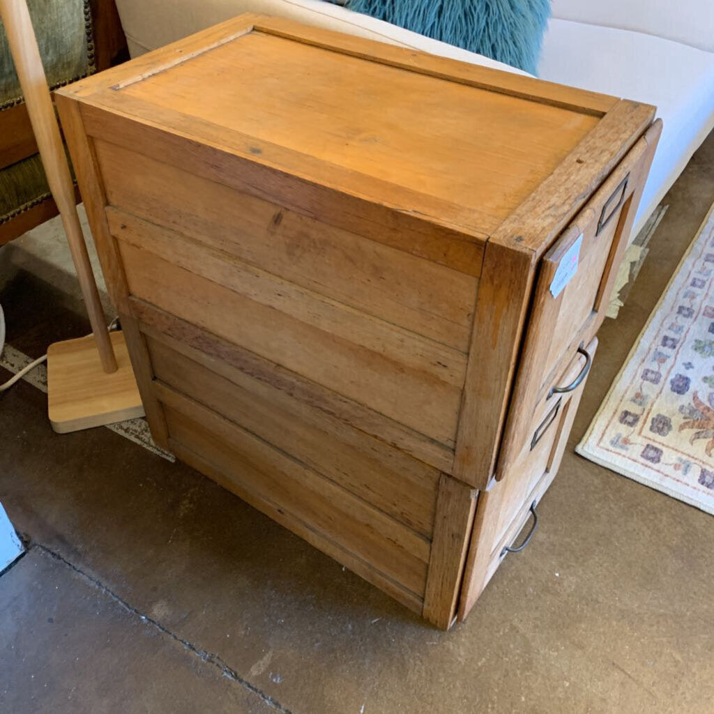 Wooden drawer unit on a floor with a broom in the background
