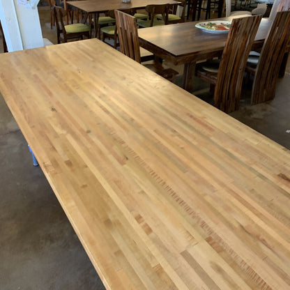 Long wooden table in a dining area with chairs and tables in the background