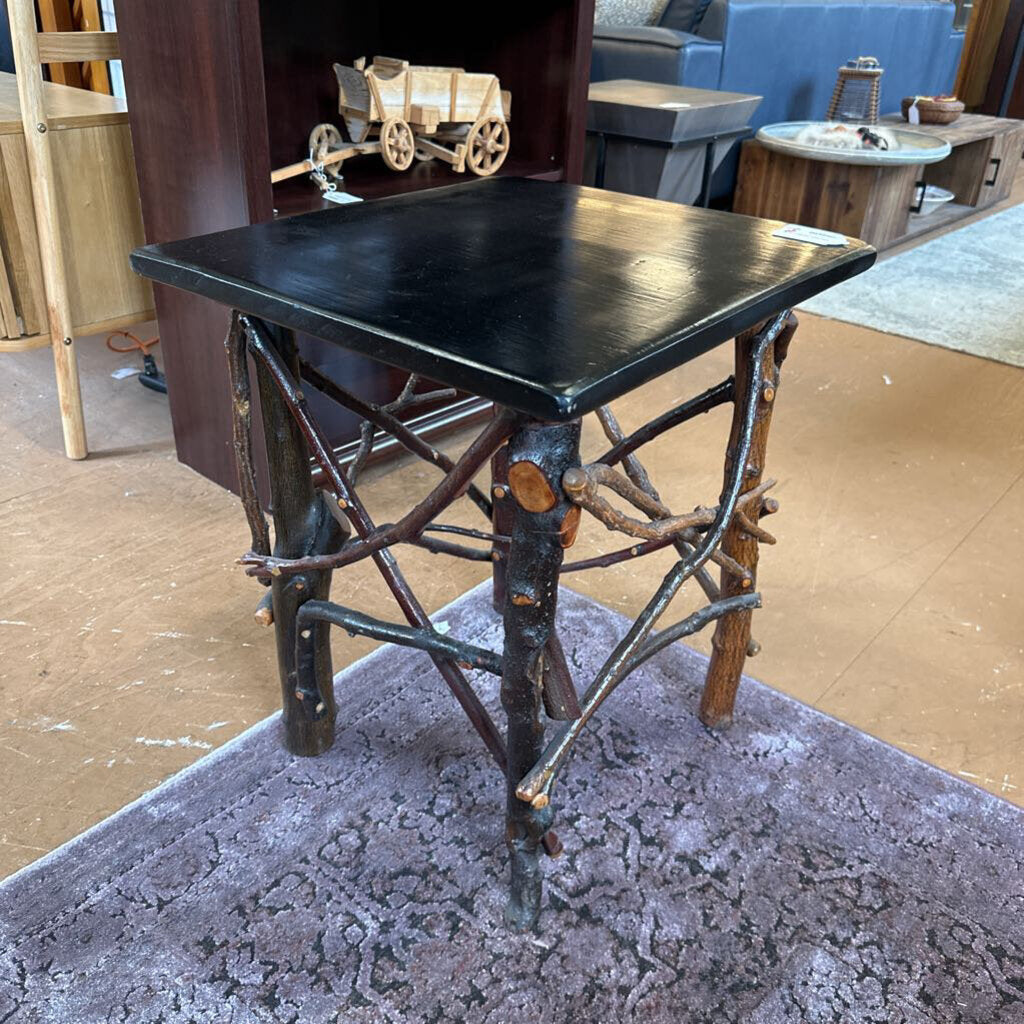 Black metal table with rustic branch design on a carpeted floor