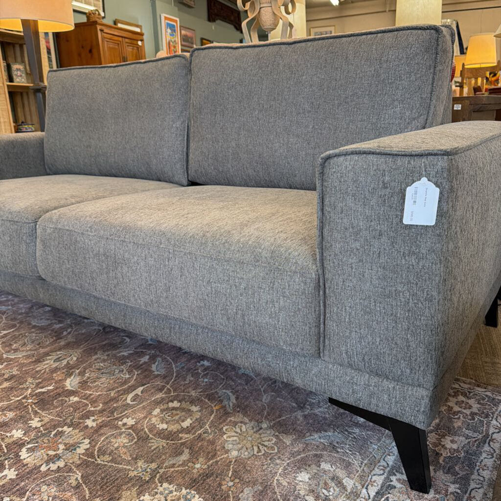 Gray sofa with a price tag in a store setting