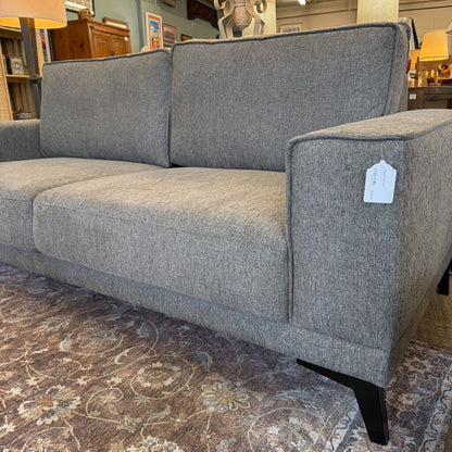 Gray sofa with a price tag in a store setting