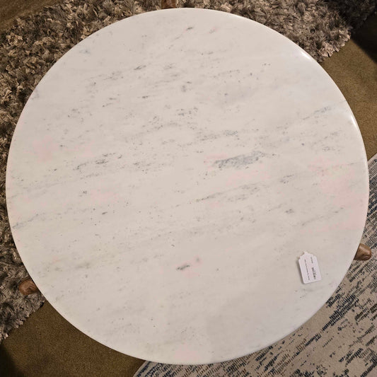 Round marble table with a visible brand tag on a textured surface
