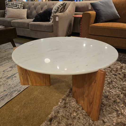 Round white marble table on a wooden base in a furniture store setting