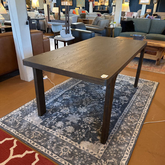 Wooden table on a patterned rug in a furniture store setting