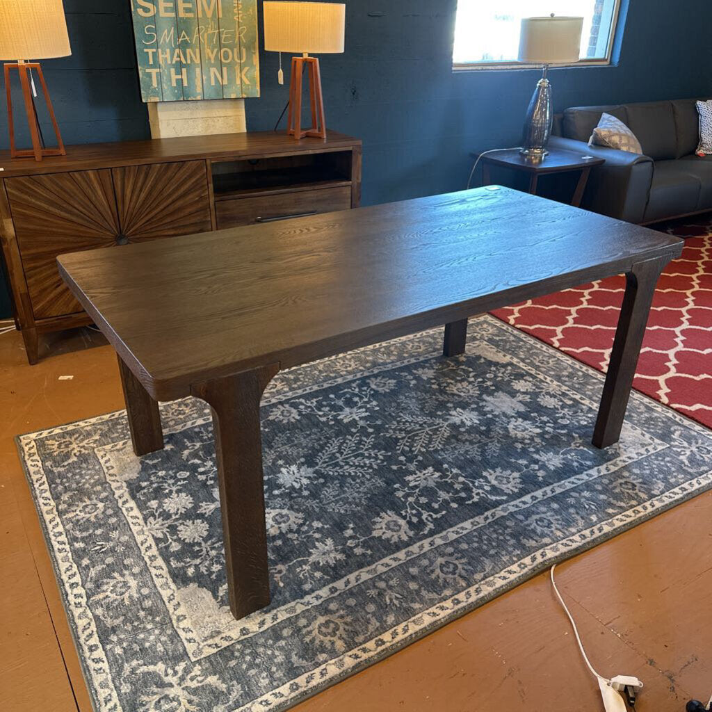 Wooden table in a room with a blue wall, sofa, and lamps.