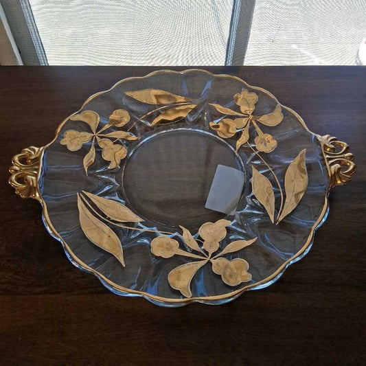 Decorative glass tray with gold leaf patterns on a dark surface