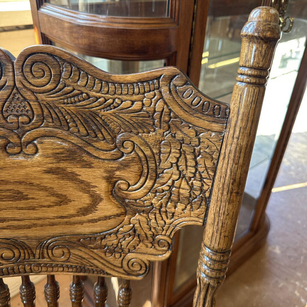 Close-up of a wooden chair with intricate carvings in a room setting.