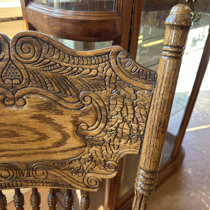 Close-up of a wooden chair with intricate carvings in a room setting.