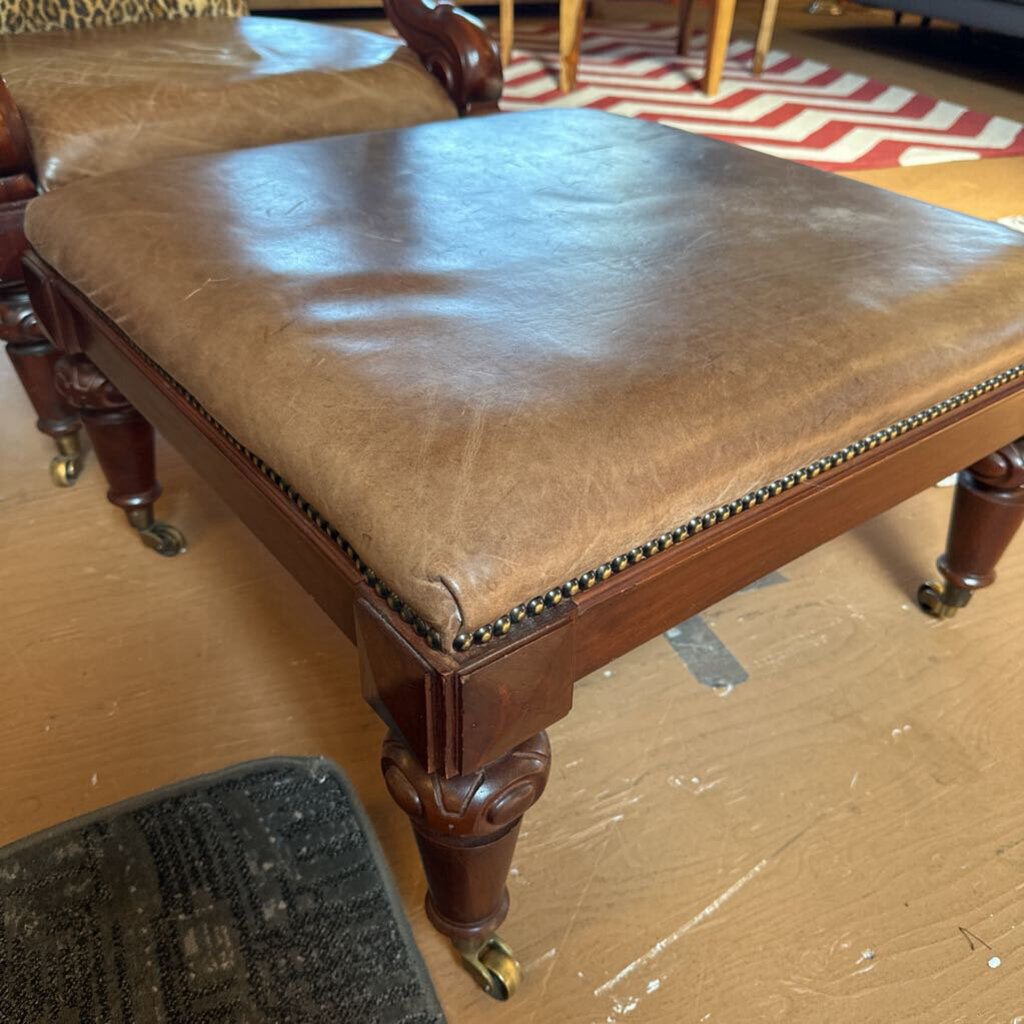 Brown leather stool with wooden legs on a wooden floor