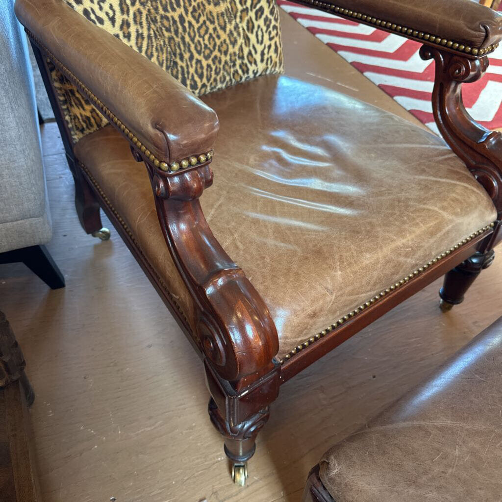 Brown leather armchair with leopard print backrest on a wooden floor.