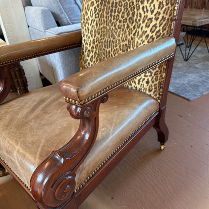 Chair with leopard print backrest and brown leather seat in a room setting.