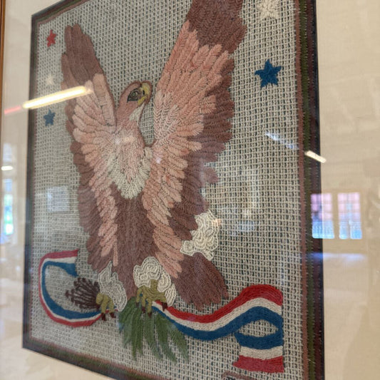 Embroidered artwork of an eagle with a flag on a textured background
