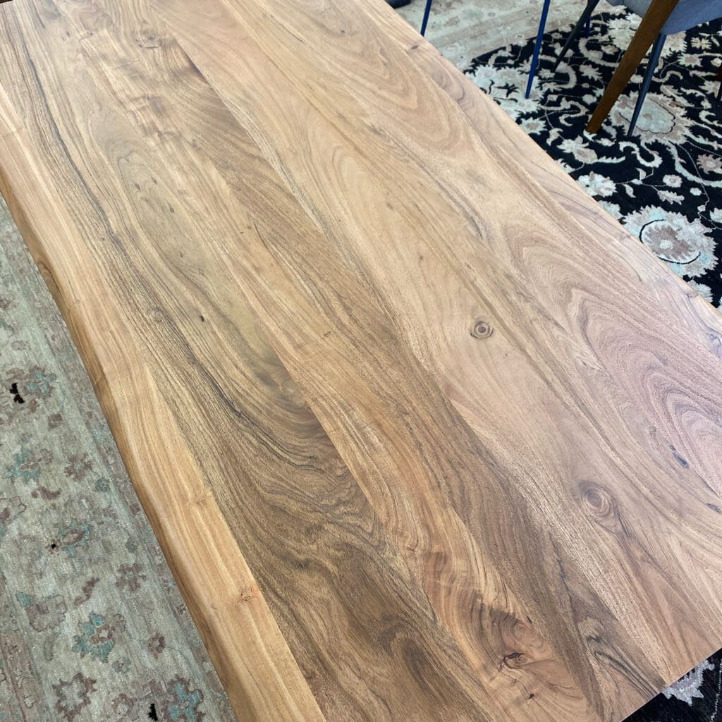 Wooden table top with a natural finish on a patterned rug
