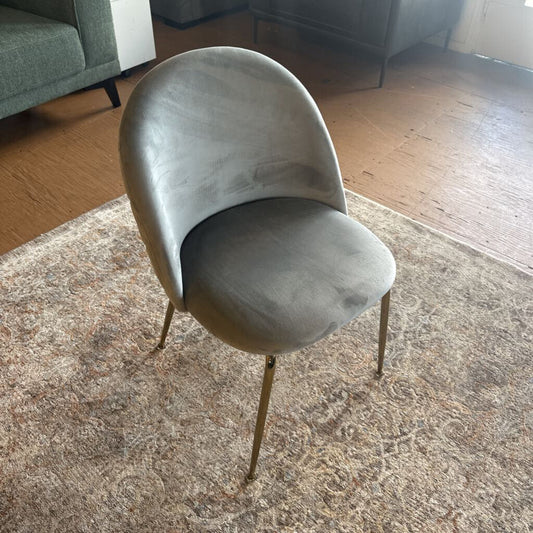 Gray chair with gold legs on a patterned rug in a room with a couch.