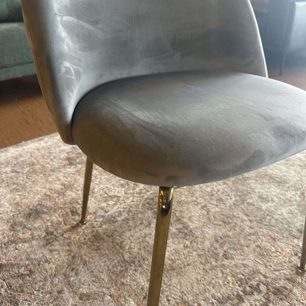 Gray chair with gold legs on a textured floor