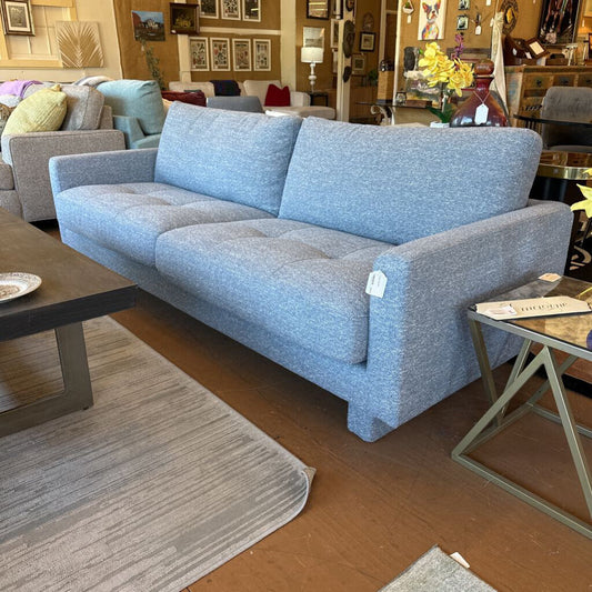 Blue sofa in a living room setting with furniture and decor around it.