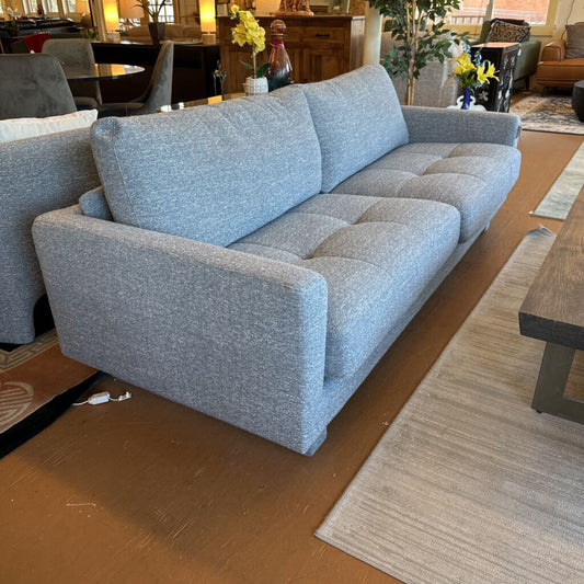 Gray sofa in a room with wooden flooring and furniture.