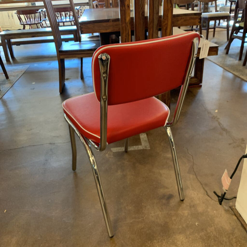 Red chair with chrome legs on a concrete floor in a warehouse setting