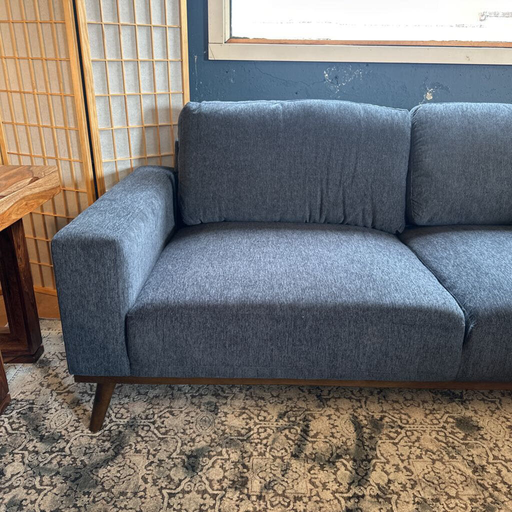 Gray sofa in a room with a patterned rug and wooden side table.
