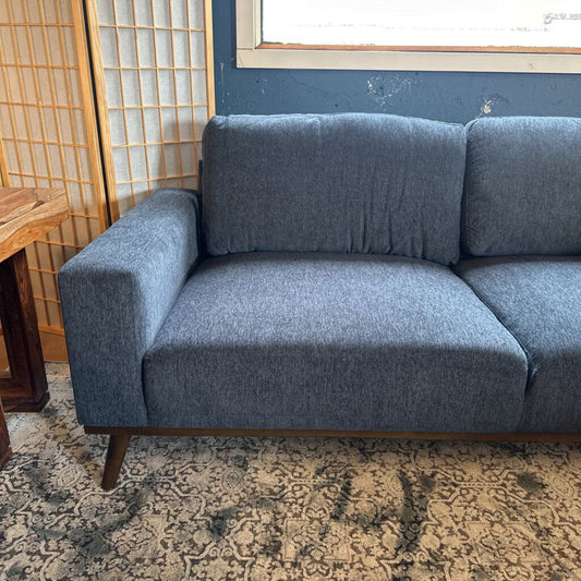 Gray sofa in a room with a patterned rug and wooden side table.