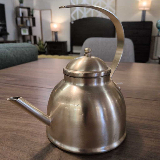 Silver kettle on a wooden table with a blurred indoor setting