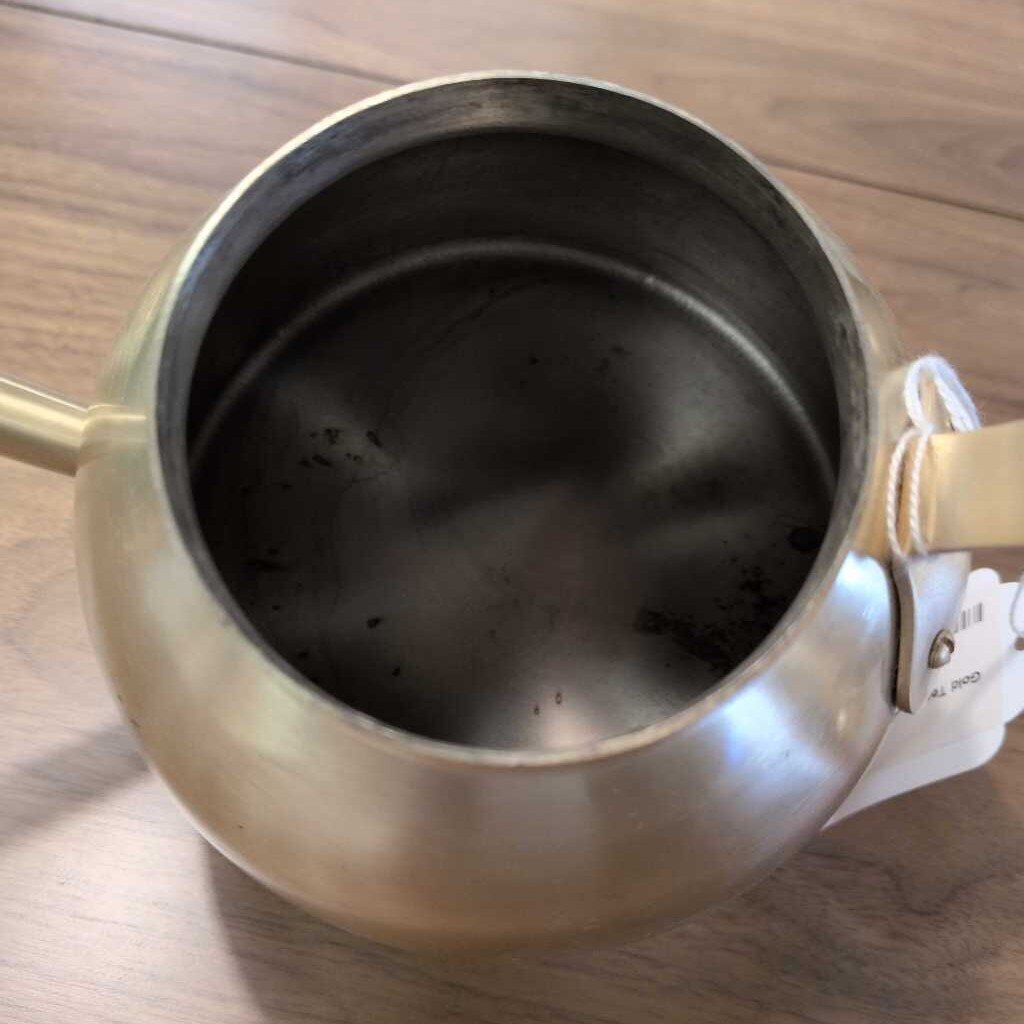 Tea pot with a tea bag inside on a wooden surface