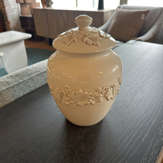 Beige ceramic jar with lid on a dark surface
