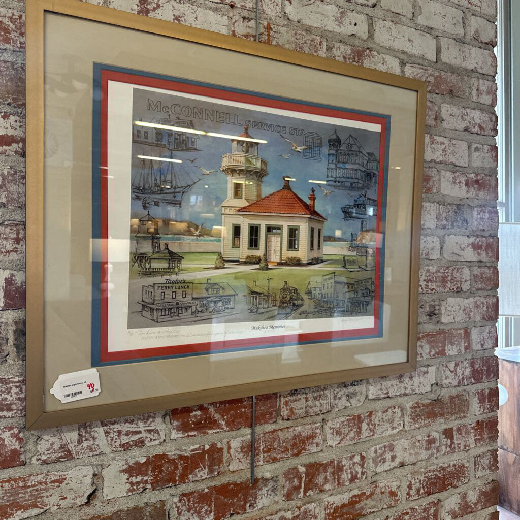 Framed artwork of a lighthouse scene on a brick wall