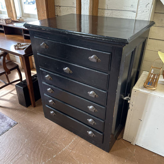 Black dresser with silver handles in a room with wooden floor and furniture.