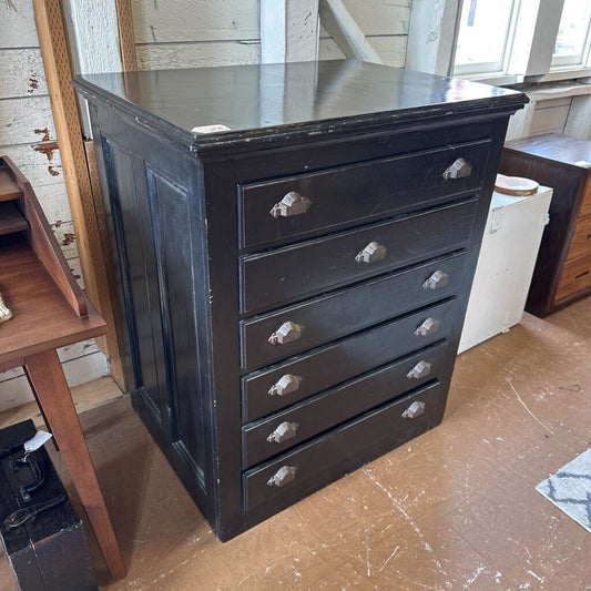 Black dresser with multiple drawers in a room setting
