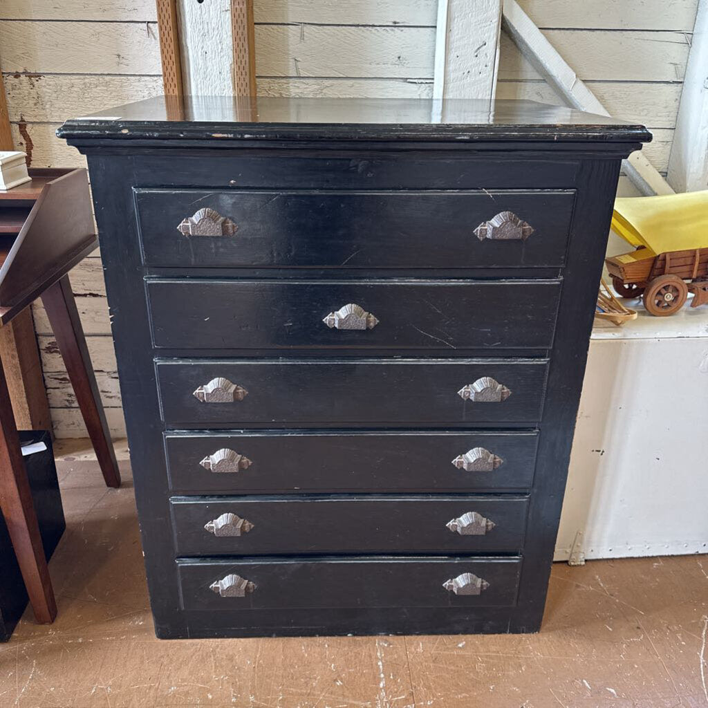 Black dresser with silver handles in a room with wooden floor and white wall.