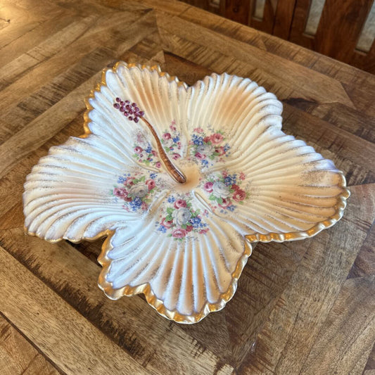 Decorative shell-shaped dish with floral patterns on a wooden surface