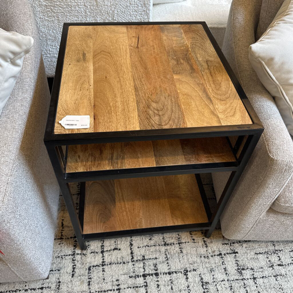 Wooden side table with black frame next to a sofa on a patterned rug