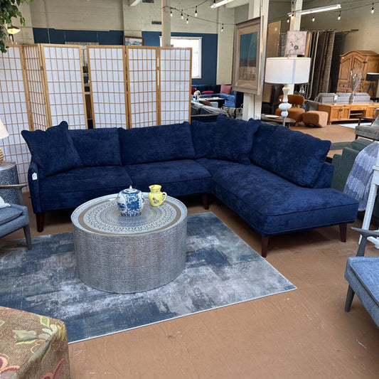 Blue sectional sofa in a room with a rug and decorative items.
