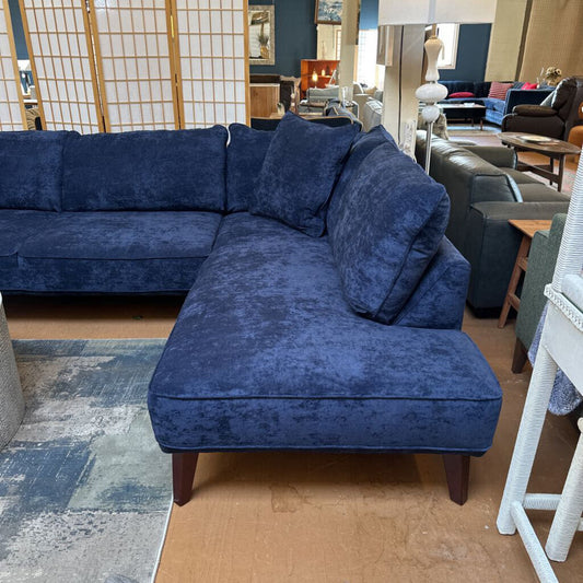 Blue sectional sofa in a room with wooden flooring and a rug.