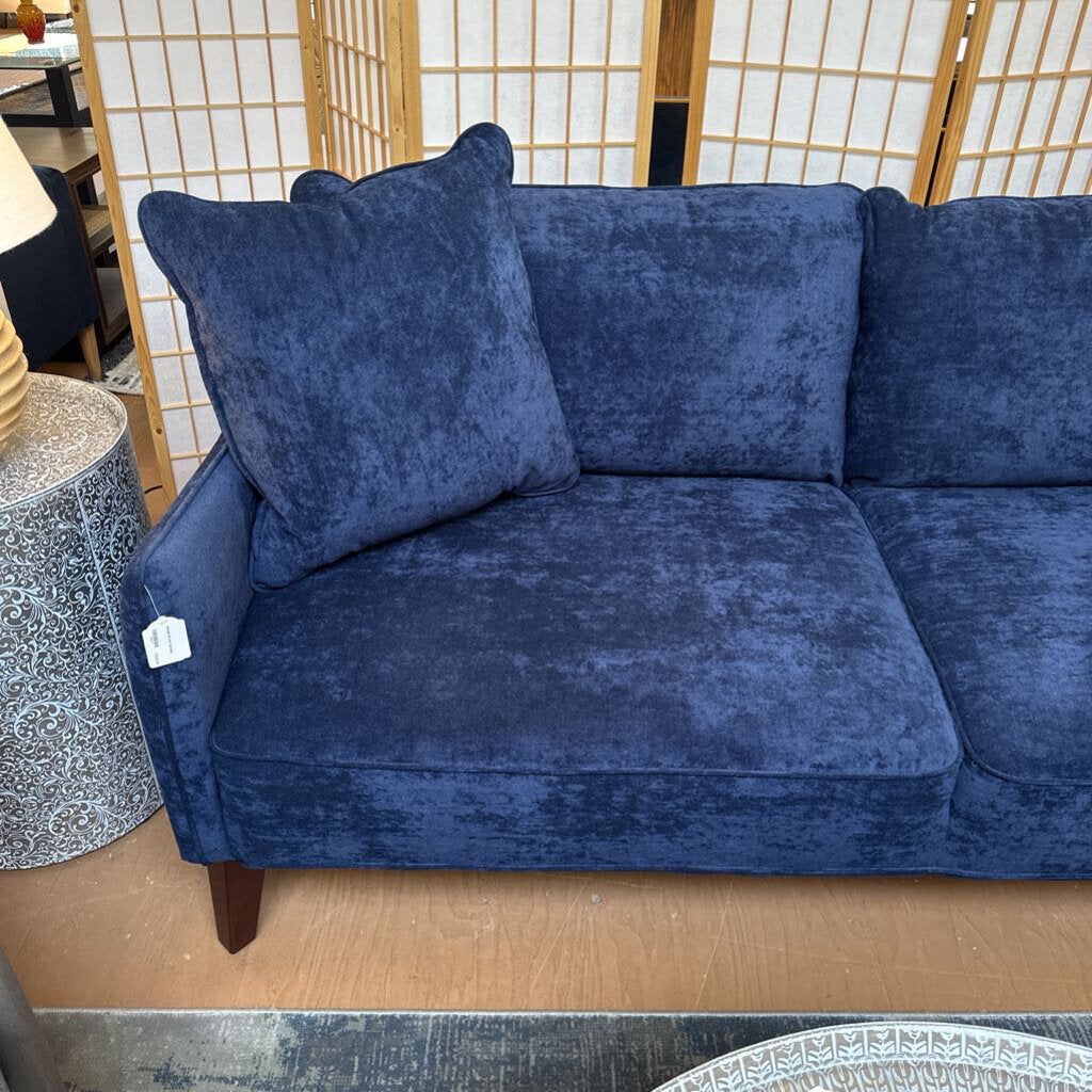 Blue velvet sofa in a room with a wooden screen and side table.