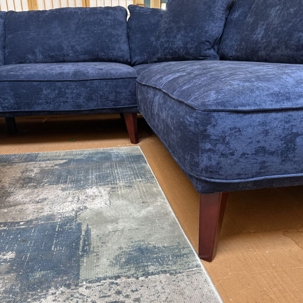 Blue sectional sofa in a room with a textured rug on the floor.