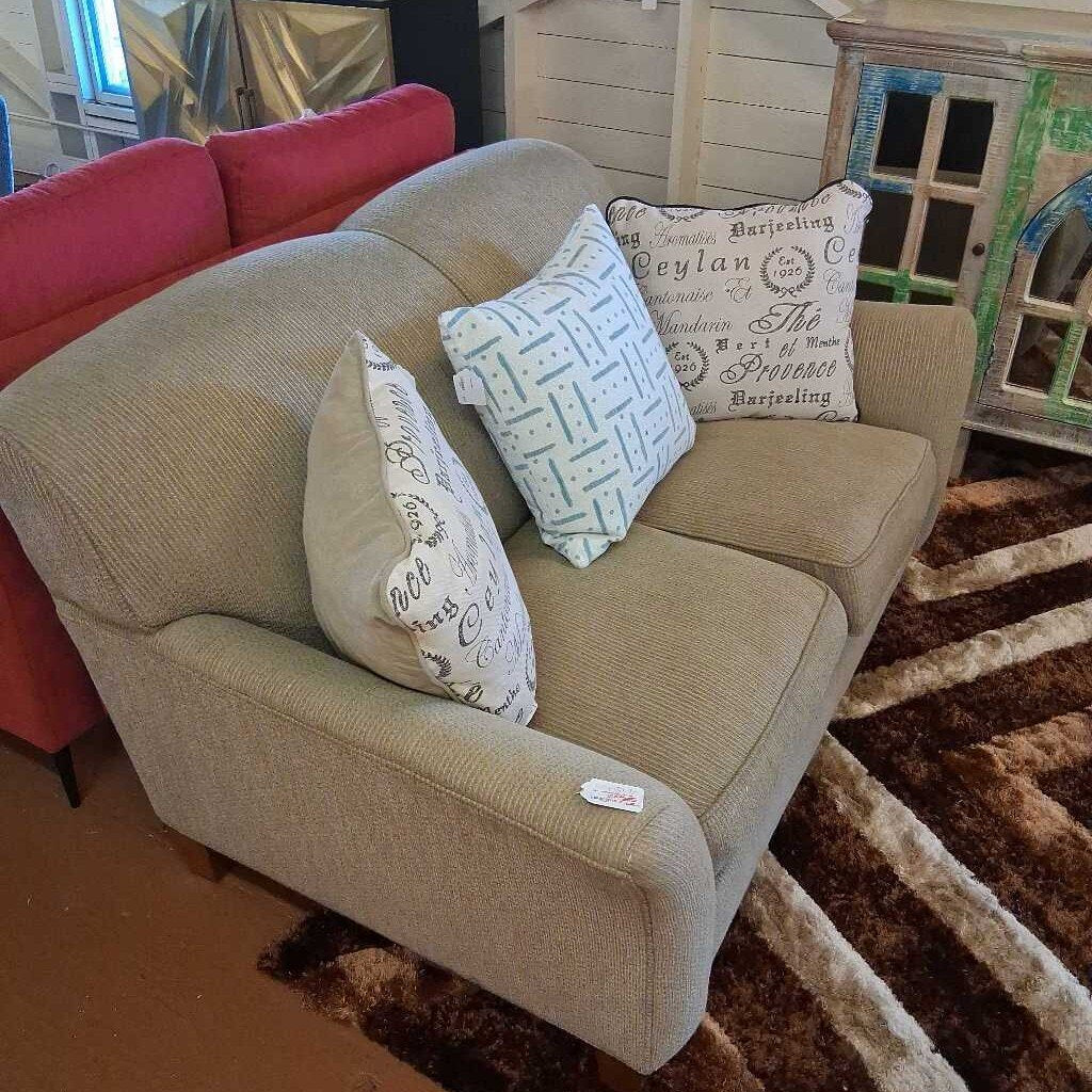 Beige sofa with decorative pillows on a brown and beige striped rug