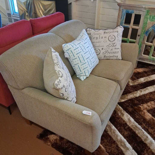 Beige sofa with decorative pillows on a brown and beige striped rug