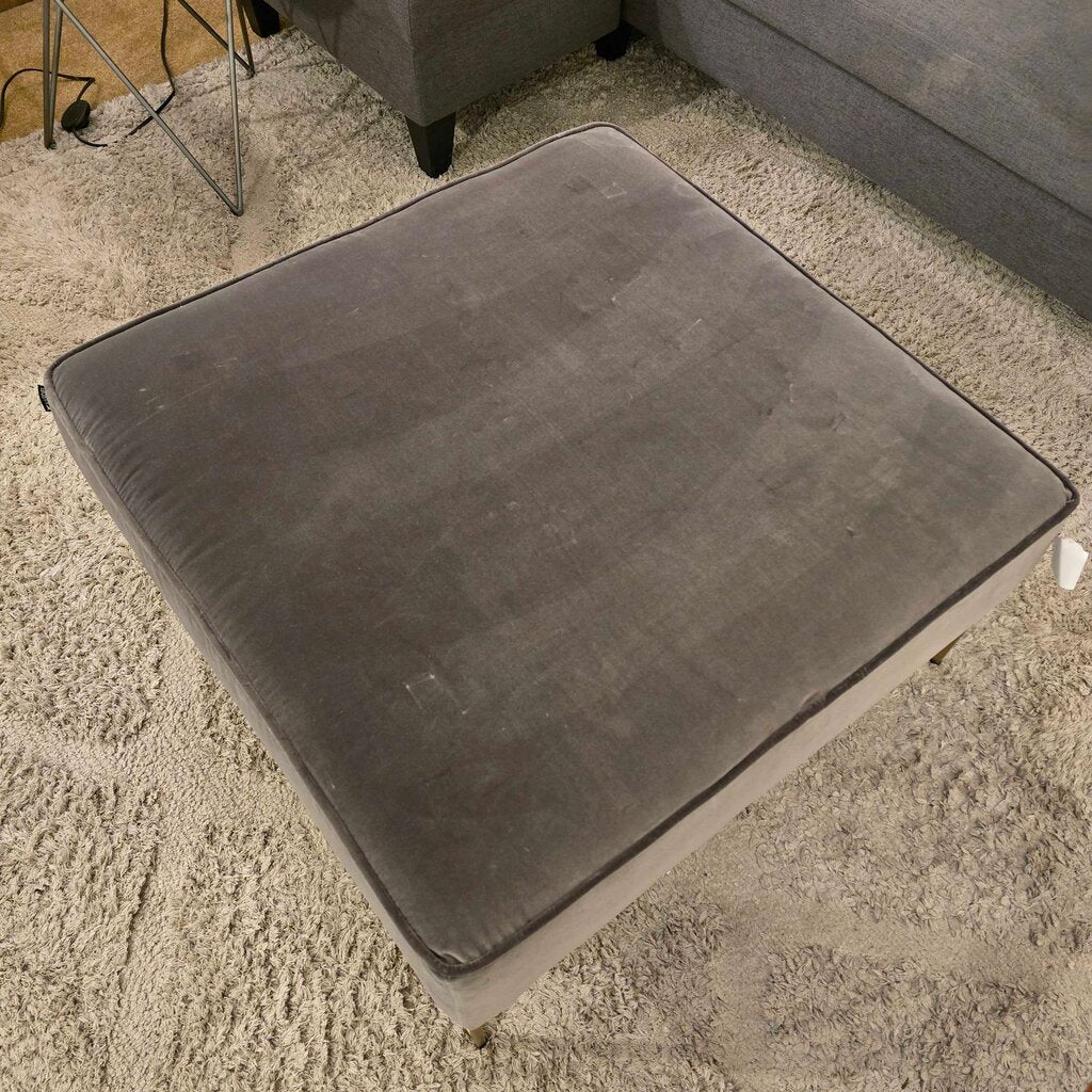 Gray ottoman on a carpeted floor