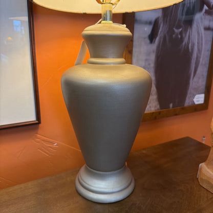 Gray lamp on a wooden surface with an orange wall in the background