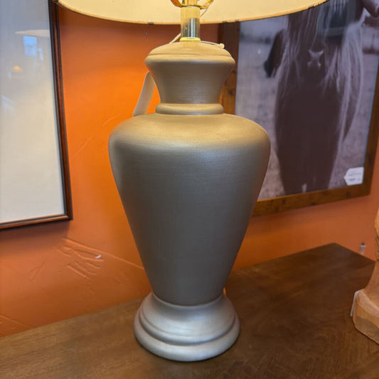 Gray lamp on a wooden surface with an orange wall in the background