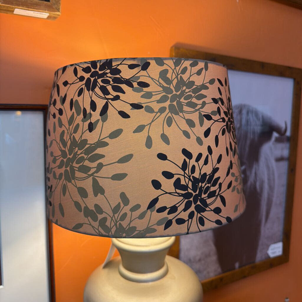 Lamp with a floral patterned shade on an orange wall.