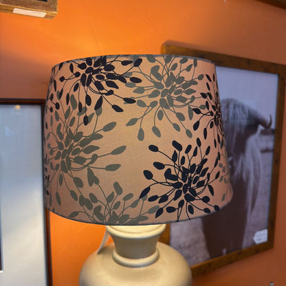 Lamp with a floral patterned shade on an orange wall.