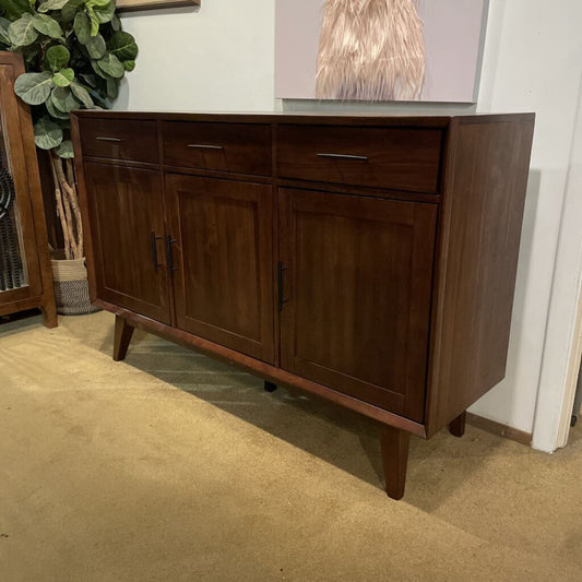Wooden sideboard with drawers and doors in a room setting.
