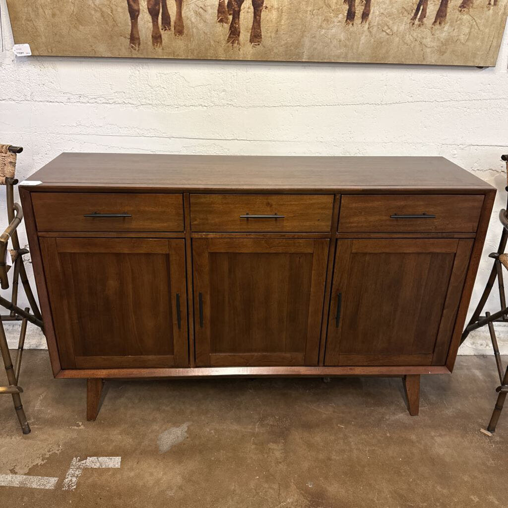 Wooden sideboard with drawers and doors in a room setting.