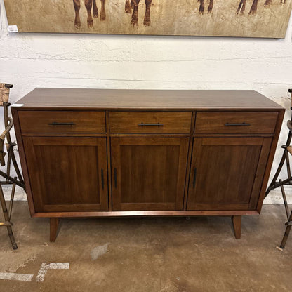 Wooden sideboard with drawers and doors in a room setting.